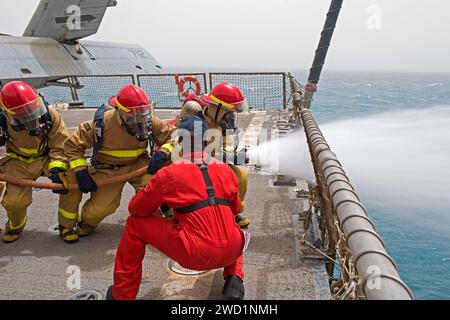 Damage Controlman Fireman führt eine Feuerwehrschlauchbohrung mit Seeleuten der ägyptischen Marine an Bord der USS Truxtun durch. Stockfoto