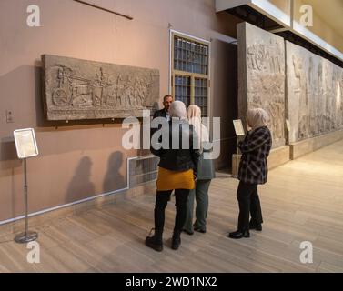 Besucher und Reiseleiter, geschnitzte Steinreliefs, Assyrischer Palast von Dur-Sharrukin („Festung von Sargon“; Chorsabad, Irak, jetzt im Irak Museum, Bagdad Stockfoto