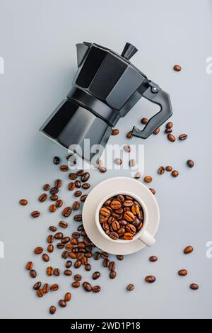 Bialetti Mokakanne. Kaffeemaschine und Kaffeebohnen im Becher auf grauem Hintergrund. Draufsicht. Stockfoto