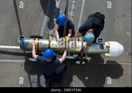 Die Matrosen sichern einen Mark 46 Mod 5A Torpedo auf dem Flugdeck an Bord der USS Howard. Stockfoto