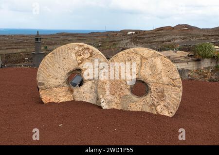 Nahaufnahme eines alten Mühlsteins. Vulkanische Landschaft im Hintergrund. Gesehen in der Nähe des Kaktusgartens auf Lanzarote. Landwirtschafts- und Landwirtschaftskonzept. Stockfoto