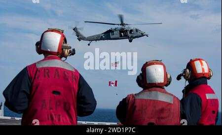 Seeleute beobachten einen MH-60S Sea Hawk während einer Luftkraftdemonstration an Bord der USS Dwight D. Eisenhower. Stockfoto