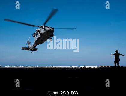 Aviation Boatswain's Mate signalisiert einen MH-60S Sea Hawk Hubschrauber auf dem Flugdeck an Bord der USS Wasp. Stockfoto