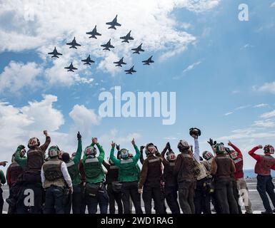 Die Segler feiern, als die ihrer Staffel zugeordneten Flugzeuge über den Flugzeugträger USS George H.W. Bush fliegen. Stockfoto