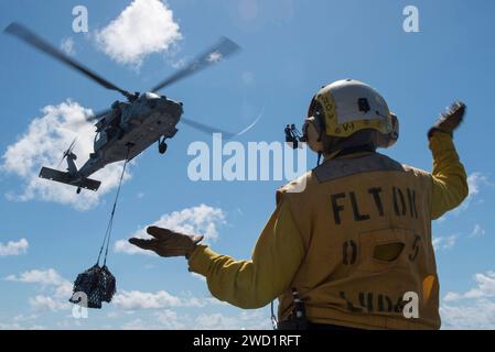 Boatswain's Mate meldet einen MH-60S Sea Hawk Hubschrauberpiloten während einer vertikalen Auffüllung. Stockfoto