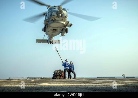 Seeleute bereiten sich darauf vor, während des Trainings zur vertikalen Auffüllung einen Anhänger an einem MH-60R Sea Hawk Hubschrauber anzubringen. Stockfoto