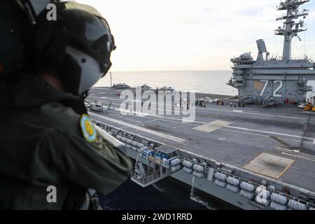 Der Marine Aircrewman blickt aus der Tür eines MH-60R Sea Hawk Hubschraubers über der USS Abraham Lincoln. Stockfoto