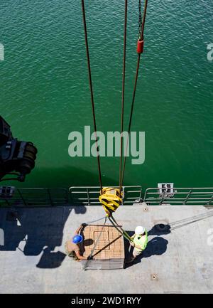 Seemanns der US Navy laden Vorräte an Bord des Schnelltransportschiffs USNS Spearhead. Stockfoto