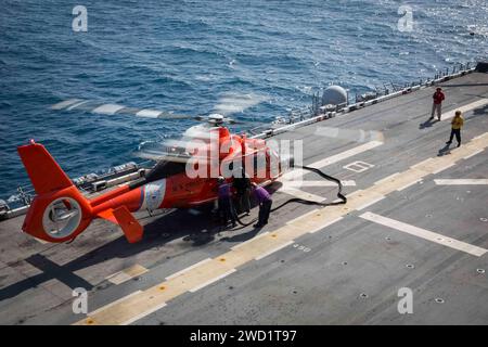 Seeleute tanken einen MH-60 Dolphin Hubschrauber der US Coast Guard auf dem Flugdeck der USS Kearsarge. Stockfoto