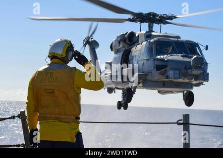 Boatswain's Mate meldet einen MH-60R Sea Hawk Hubschrauber während einer vertikalen Auffüllung. Stockfoto