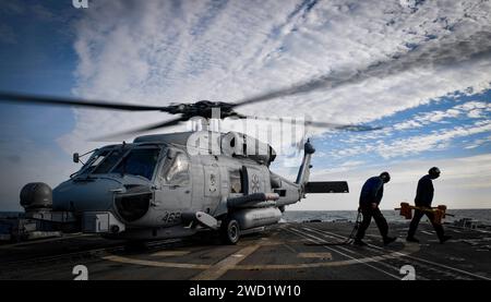 Seeleute entfernen Keile und Ketten von einem MH-60R Sea Hawk Hubschrauber an Bord der USS Oscar Austin. Stockfoto