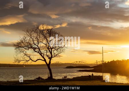 Ein wunderschöner Sonnenuntergang im Firth of Forth mit Blick auf Downing Point in Dalgety Bay und die Forth Bridge. Stockfoto