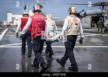 Seeleute transportieren einen Patienten zu einem nahe gelegenen MH-60 S Sea Hawk Hubschrauber an Bord der USNS Comfort. Stockfoto