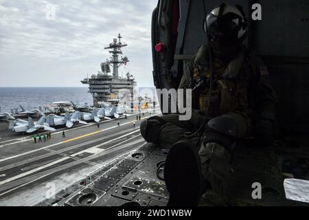 Die Marine Air Crewman sitzt in einem MH-60S Sea Hawk Hubschrauber, während sie vom Flugdeck der USS Theodore Roosevelt aus startet. Stockfoto