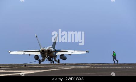 Ein Sailor läuft aus, um das an einer F/A-18E Super Hornet angebrachte Fanggerät zu entfernen. Stockfoto