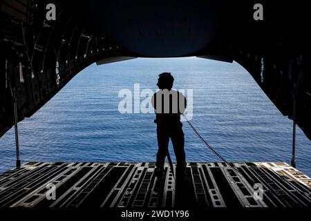 Ein Mitglied der U.S. Air Force beobachtet während einer Nutzlastlieferung von den Haupttüren eines C-17 Globemaster III aus. Stockfoto