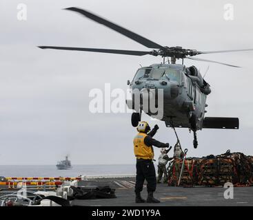 Aviation Boatswain's Mate steuert einen MH-60S Sea Hawk Hubschrauber auf dem Flugdeck der USS Makin Island. Stockfoto