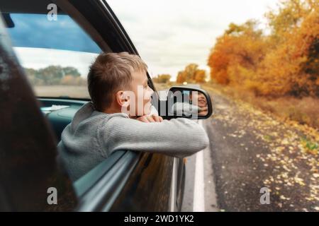 Junge, der seine Köpfe und Hände aus dem Auto nimmt Stockfoto