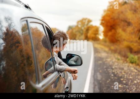 Junge, der seine Köpfe und Hände aus dem Auto nimmt Stockfoto