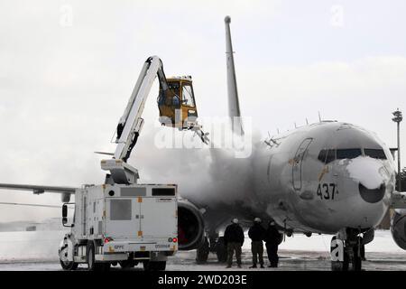 Aviation Machinist's Mate betreibt einen Enteisungswagen, um Schnee und Eis von einem P-8A Poseidon zu entfernen. Stockfoto