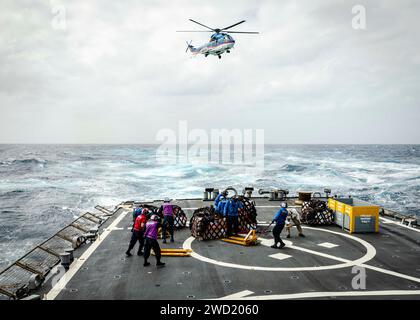 Seeleute transportieren Paletten mit Fracht vom Flugdeck der USS John S. McCain während einer Auffüllung auf See. Stockfoto