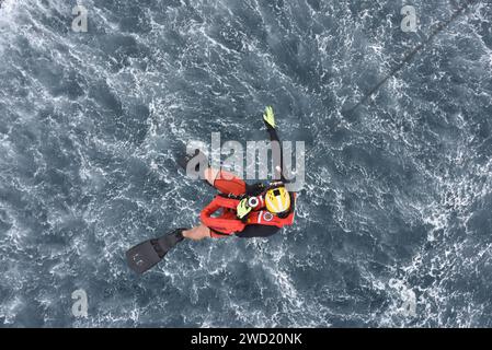 Ein Survival-Techniker wird von einem MH-60 Jayhawk Hubschrauber ins Wasser gesenkt. Stockfoto