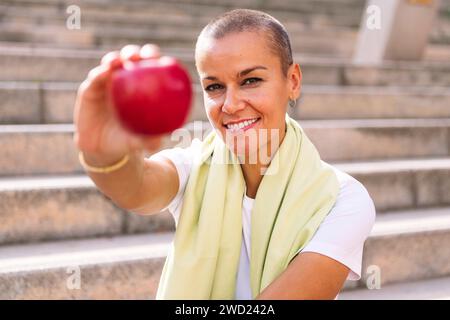 Junge Sportfrau zeigt nach dem Training einen Apfel Stockfoto