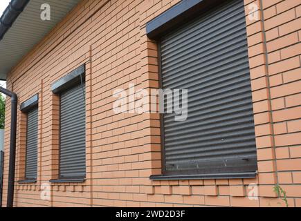 Rollläden bieten Fensterschutz. Backsteinhaus mit Rollläden an den Fenstern Stockfoto