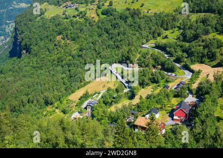 Eine malerische, gewundene Bergstraße mit einem roten, zweistöckigen Haus im beliebten Touristenziel Geiranger, Norwegen, das zum UNESCO-Weltkulturerbe gehört Stockfoto