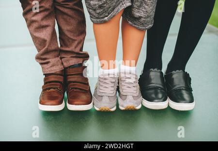 Modische Schuhe für Kinder. Drei Paar Kinderfüße mit bequemen und modischen Sportschuhen. Back-to-School-Konzept Stockfoto