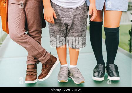 Modische Schuhe für Kinder. Drei Paar Kinderfüße mit bequemen und modischen Sportschuhen. Back-to-School-Konzept Stockfoto