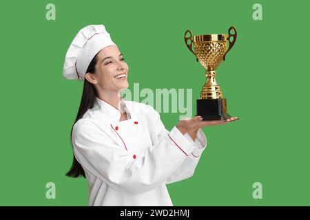 Weibliche Köchin mit goldener Tasse auf grünem Hintergrund Stockfoto