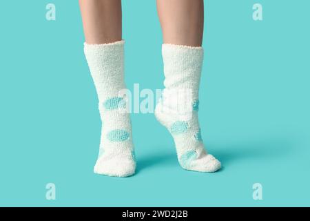 Beine einer jungen Frau in warmweißen gepunkteten Socken auf blauem Hintergrund Stockfoto