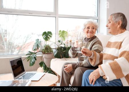 Ältere Freundinnen trinken Champagner auf dem Sofa zu Hause Stockfoto