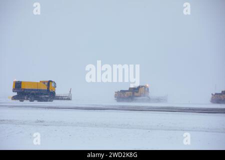 Der Flughafen ist bei starkem Schneefall geschlossen. Schneepflüge entfernen Schnee von der geschlossenen Piste. Wetterextremen im Transport mit Kopierraum. Stockfoto