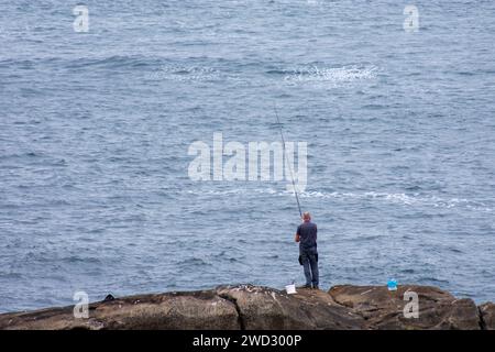 Ein einsamer Fischer fischt mit einer Rute in den Felsen von Bayonne nach Barsch Stockfoto