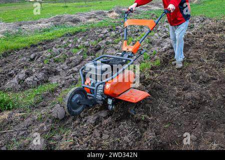 Die landwirtschaftliche Landschaft verändert sich unter dem Einfluss eines engagierten Landwirts und eines robusten Motorgrubber und bereitet den Boden für den Anbau vor. Stockfoto