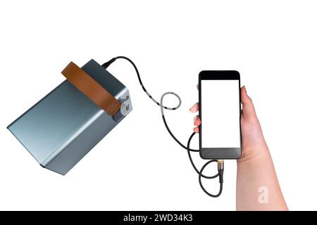 Smartphone mit einem leeren weißen Bildschirm in der Hand, das über ein USB-Kabel auf weißem Hintergrund von einer Powerbank aufgeladen wird. Mobile Stromversorgung Stockfoto