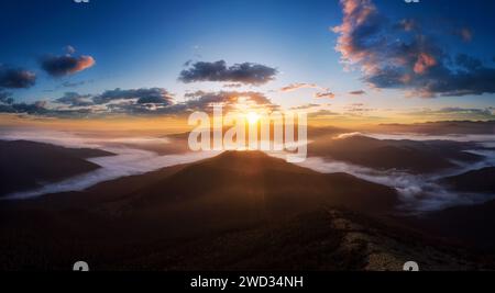 Dramatische Landschaft in Karpaten mit Morgennebel im Tal und wunderschönem Himmel bei Sonnenaufgang. Stockfoto