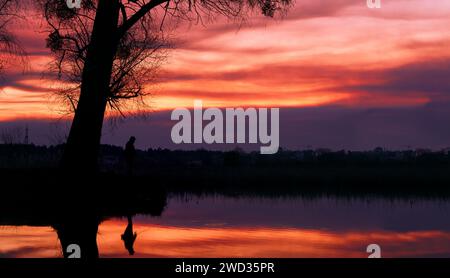 Silhouette eines Fischers auf dem See vor der Kulisse eines dramatischen Sonnenuntergangs. Stockfoto