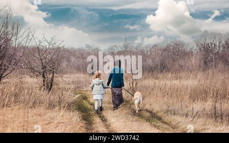 Mutter und Tochter gehen mit Hund auf dem Feldweg Stockfoto