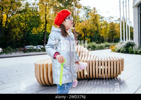 Seitenansicht eines kleinen Mädchens mit Brille in der Stadtstraße draußen. Stockfoto