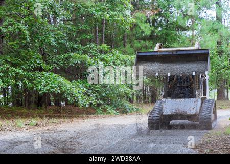 Eine hochgeladene Schaufel mit Schotter wird während der Bauarbeiten von einem Minilader Bobcat bewegt Stockfoto