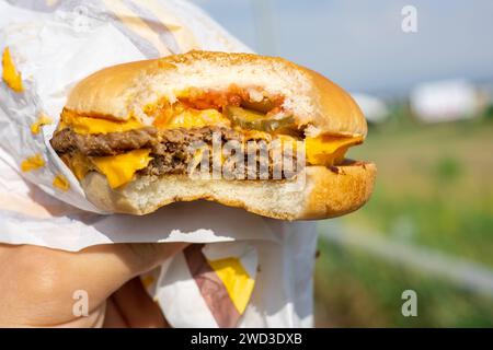 Das Konzept von Fast Food und Take-away-Food. Großer saftiger Burger mit Käse in der Hand Copyright: XDmytroxNikolaienkox Stockfoto