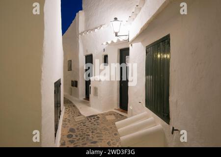 Binibèquer Vell, Menorca, Balearen, Spanien. Beleuchtete Straße zwischen weißen Dorfhäusern bei Nacht. Stockfoto