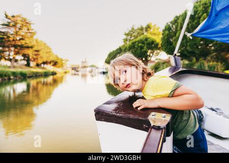 Süßer kleiner Junge, der auf dem Boot segelt. Aufnahme in Aigues-Mortes, Camargue im Languedoc-Roussillon, Frankreich Stockfoto