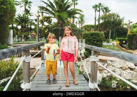 Gruppe von zwei lustigen Kindern, die Minigolf spielen, Kinder genießen Sommerurlaub Stockfoto