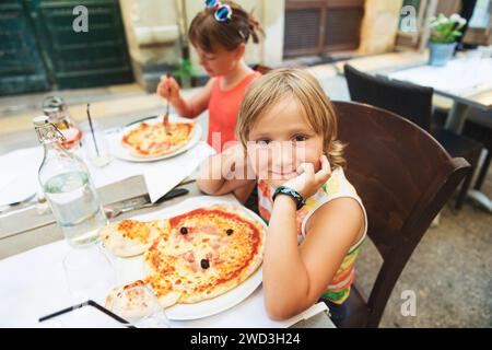 Glücklicher kleiner Junge, der im Restaurant Kinderpizza isst. Menü für Kinder, italienische Pizza in Tierform für Kinder Stockfoto