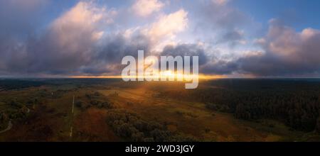 Wunderschöner Sonnenaufgang über der Landschaft mit Wald und Wiese am Herbstmorgen. Stockfoto