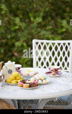 Tisch, Teeparty und Kuchen im Garten oder Cupcakes für Geburtstagsfeiern, Macarons oder Getränke. Hinterhof, Stuhl und süßes Dessert oder Essen auf der Terrasse oder Stockfoto